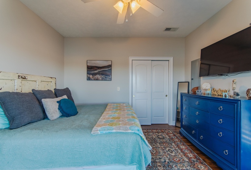 Bedroom with ceiling fan, dark hardwood / wood-style flooring, and a closet