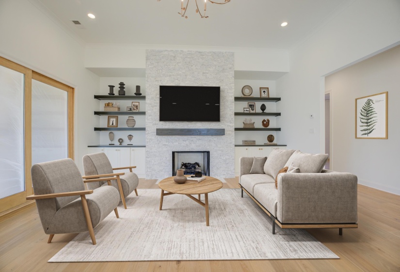 A spacious great room with rich hardwood floors, highlighted by a stunning stone fireplace as the focal point. Large sliding doors open seamlessly to the backyard, bringing in natural light and offering easy access to outdoor living.