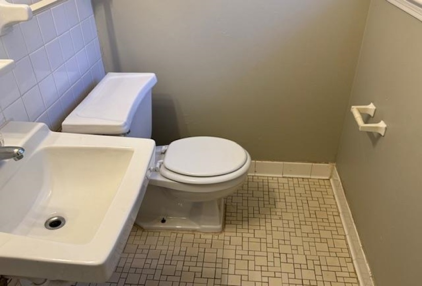 Bathroom with tile walls, tile patterned flooring, toilet, and sink
