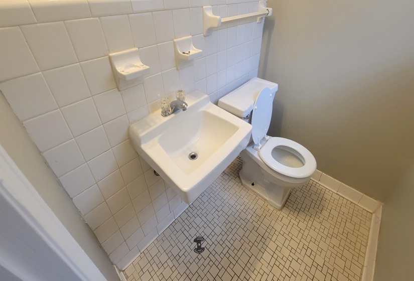 Bathroom featuring tile patterned flooring, toilet, tile walls, and sink