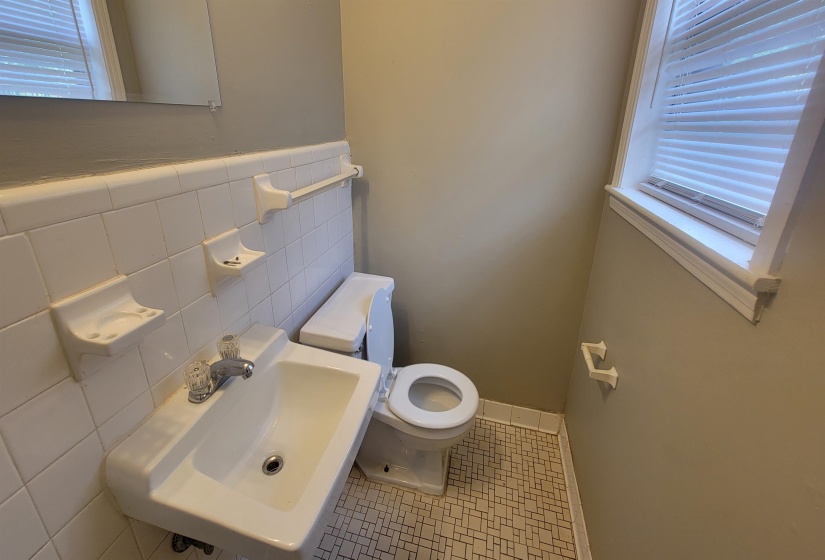 Bathroom with tile patterned floors, toilet, sink, and tile walls