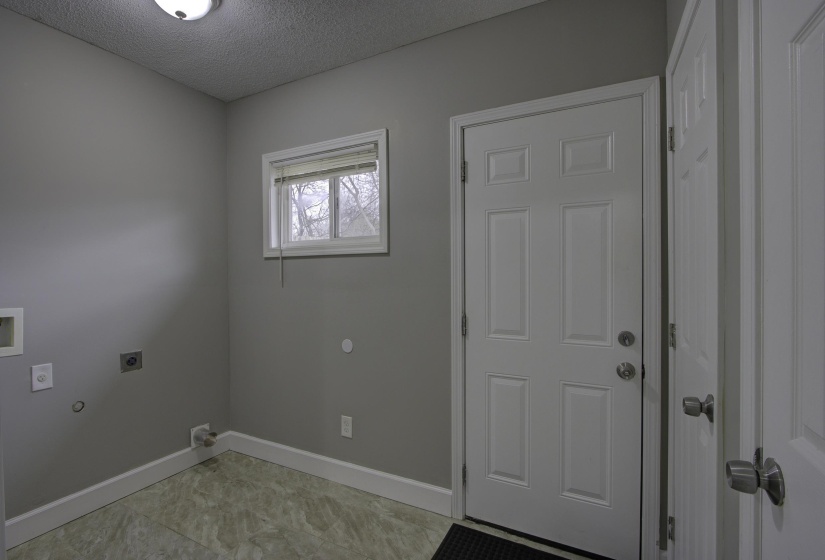 Clothes washing area featuring electric dryer hookup, gas dryer hookup, light tile patterned floors, and a textured ceiling
