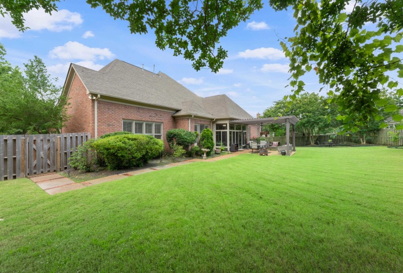 Rear view of property featuring brick siding, a shingled roof, a fenced backyard, and a patio area