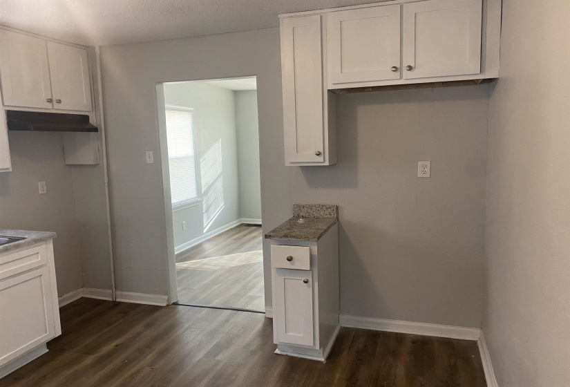 Kitchen with stone counters, white cabinetry, and dark wood-type flooring