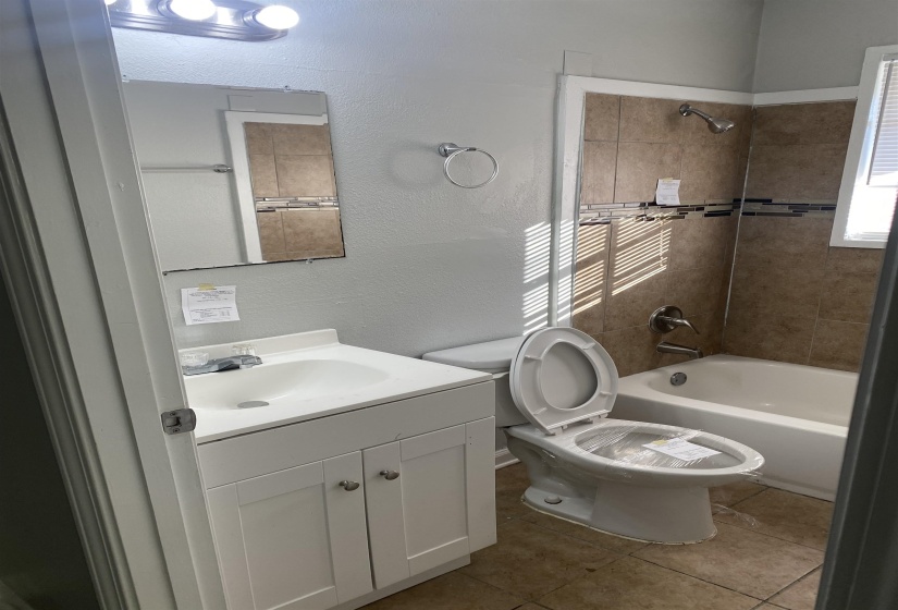 Full bathroom featuring tile patterned flooring, vanity, tiled shower / bath combo, and toilet