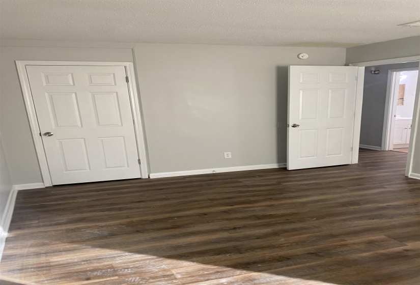 Empty room with a textured ceiling and dark hardwood / wood-style floors