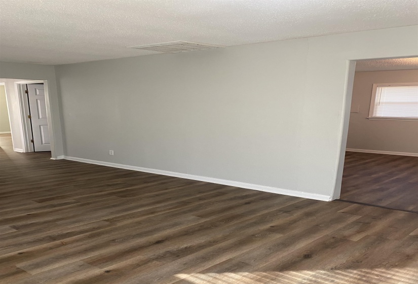 Empty room with a textured ceiling and dark wood-type flooring