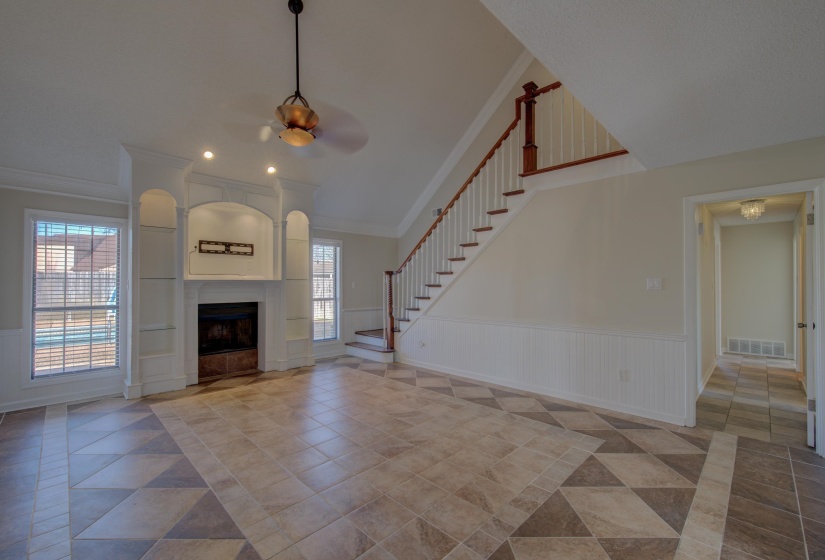 Unfurnished living room with ceiling fan, ornamental molding, a wealth of natural light, and a tiled fireplace