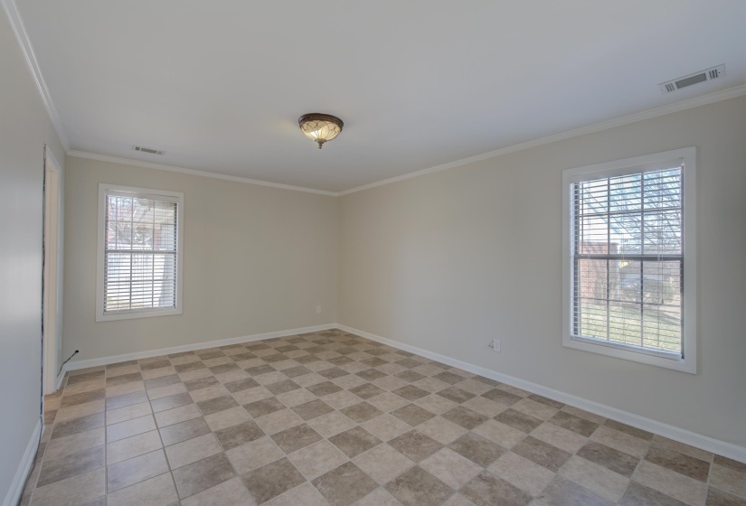Tiled empty room with a wealth of natural light and ornamental molding