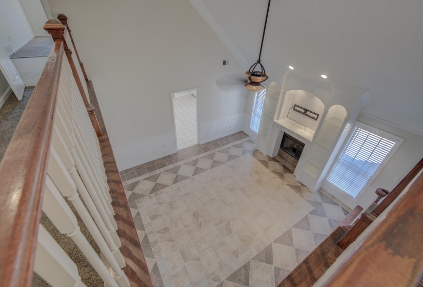 Unfurnished living room with a tile fireplace, ceiling fan, a high ceiling, crown molding, and light tile patterned floors
