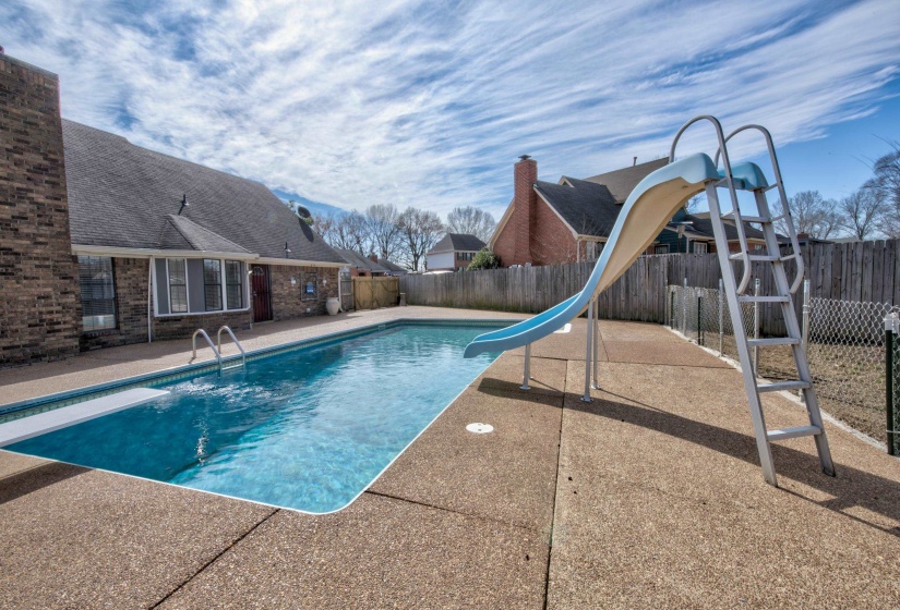 View of pool featuring a diving board, a patio area, and a water slide