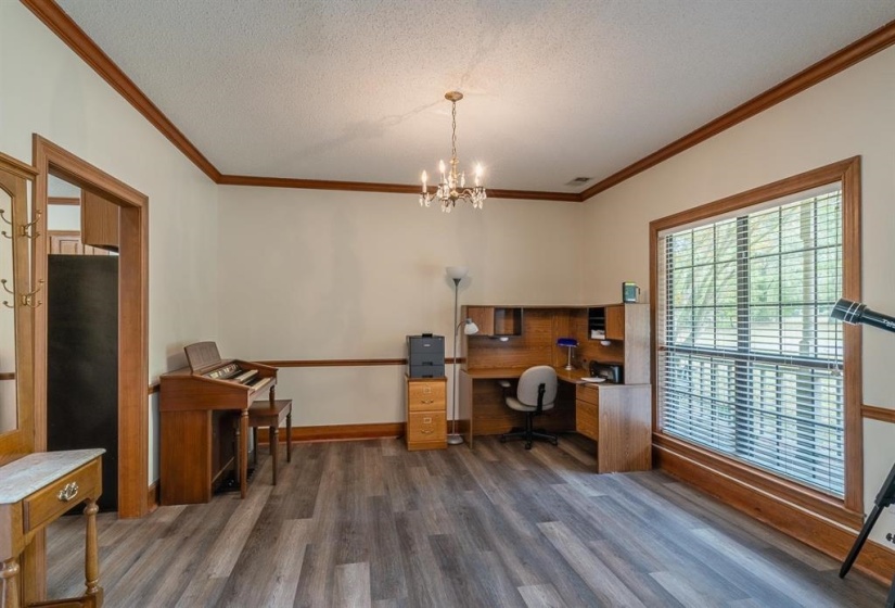 Office space featuring a textured ceiling, an inviting chandelier, dark wood-type flooring, and crown molding