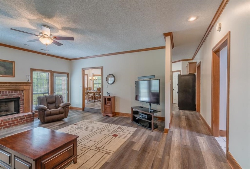 Living room with ceiling fan, ornamental molding, a fireplace, a textured ceiling, and wood-type flooring