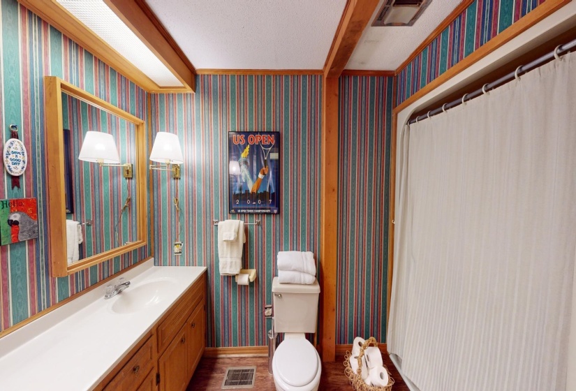 Bathroom featuring hardwood / wood-style floors, vanity, toilet, a textured ceiling, and beam ceiling