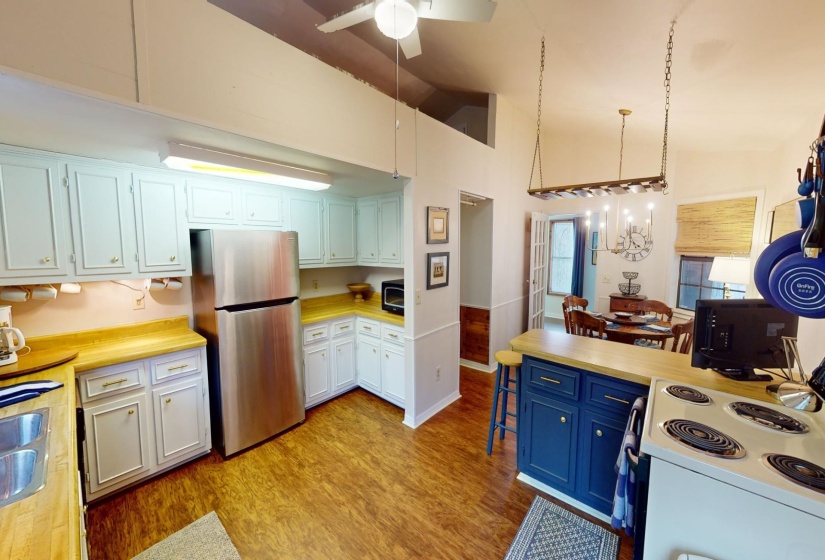 Kitchen featuring light hardwood / wood-style flooring, stainless steel fridge, pendant lighting, vaulted ceiling, and white cabinets