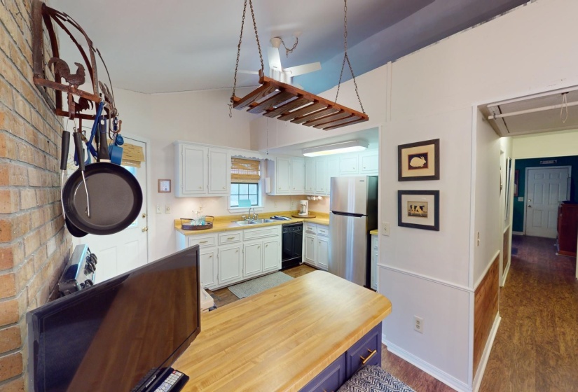 Kitchen with white cabinetry, black dishwasher, stainless steel fridge, wood-type flooring, and vaulted ceiling
