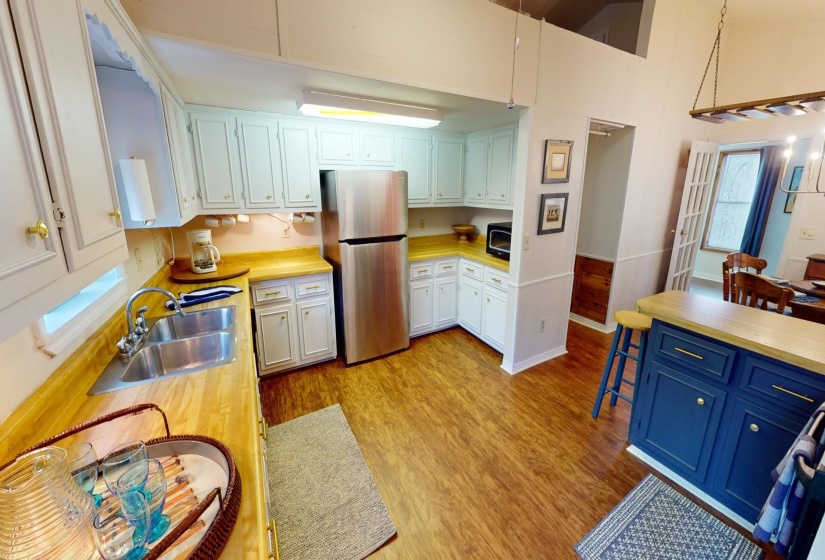 Kitchen featuring white cabinets, hanging light fixtures, sink, light wood-type flooring, and stainless steel refrigerator