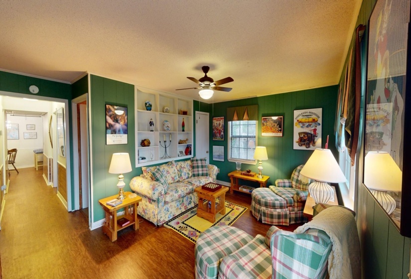 Living room featuring built in shelves, a textured ceiling, hardwood / wood-style flooring, and ceiling fan