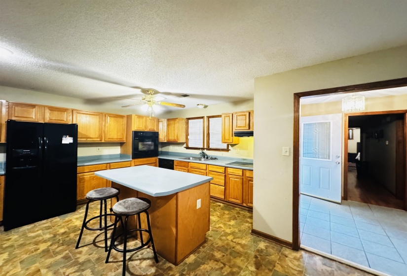 Kitchen featuring a center island, sink, a textured ceiling, a kitchen bar, and black appliances