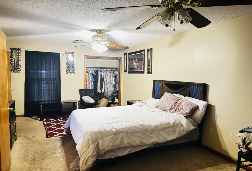 Bedroom featuring carpet, ceiling fan, a textured ceiling, and a closet