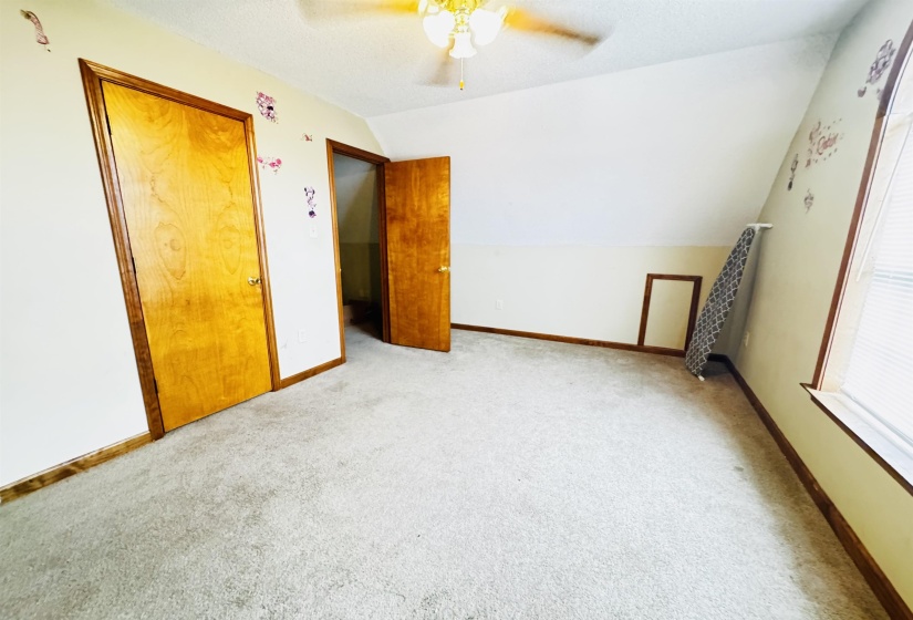 Unfurnished bedroom with ceiling fan, light carpet, and lofted ceiling