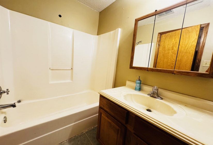Bathroom featuring tile patterned flooring, vanity, a textured ceiling, and tub / shower combination