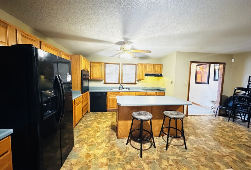 Kitchen featuring black appliances, a kitchen breakfast bar, sink, ceiling fan, and a kitchen island