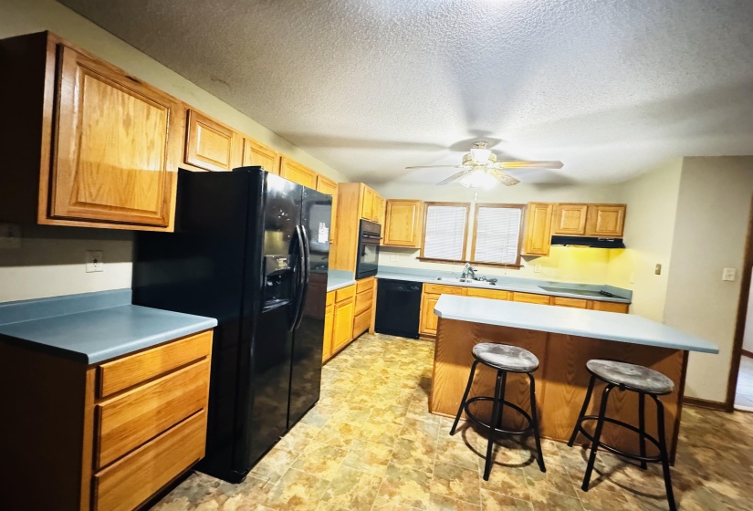 Kitchen featuring a center island, black appliances, sink, ceiling fan, and a breakfast bar area