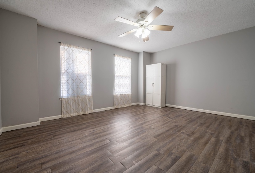 Empty room with ceiling fan, a textured ceiling, and dark wood-type flooring