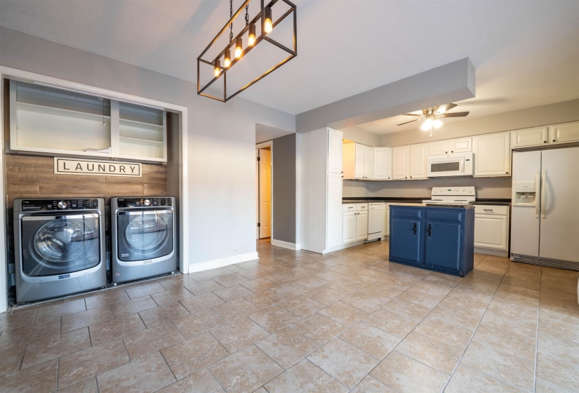 Kitchen featuring white cabinetry, separate washer and dryer, blue cabinets, white appliances, and ceiling fan with notable chandelier