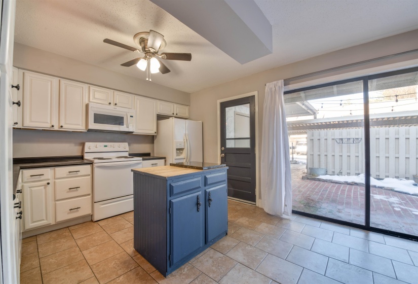 Kitchen featuring white appliances, blue cabinetry, white cabinets, butcher block countertops, and a kitchen island