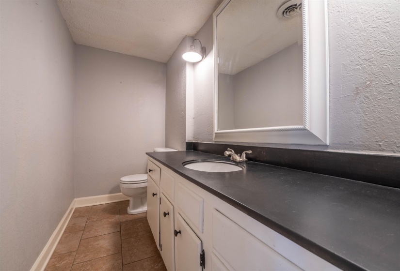 Bathroom featuring tile patterned flooring, vanity, a textured ceiling, and toilet
