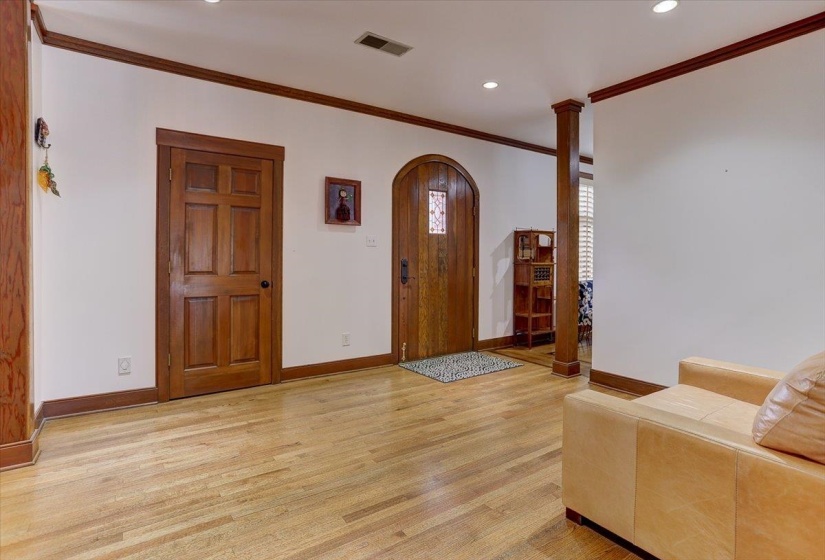 Foyer featuring visible vents, arched walkways, baseboards, ornamental molding, and light wood-style flooring