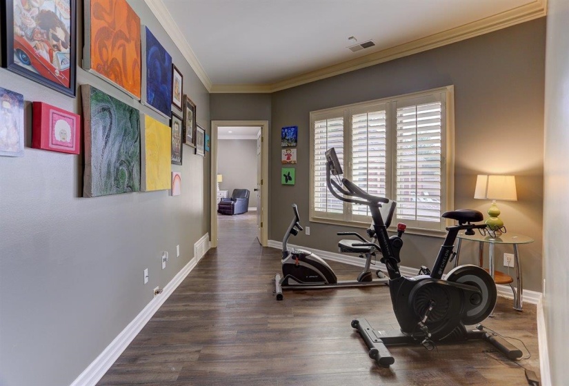 Exercise room with crown molding, baseboards, visible vents, and wood finished floors
