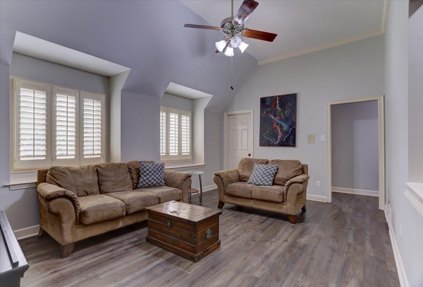 Living room with crown molding, baseboards, a ceiling fan, and wood finished floors