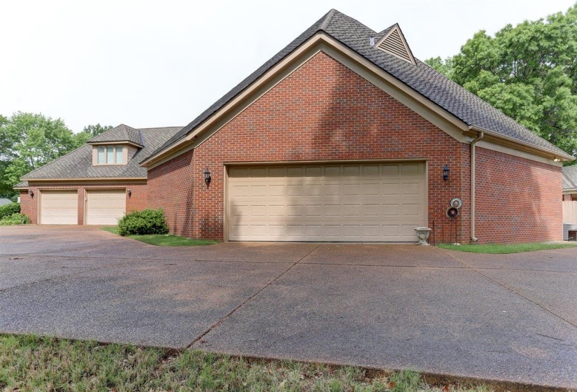 View of side of property with roof with shingles, concrete driveway, and brick siding