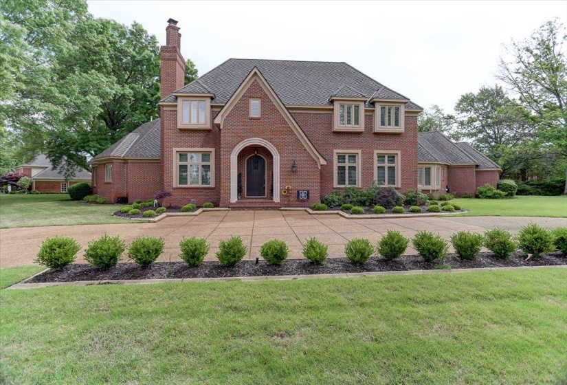 View of front of property featuring a chimney, a front yard, and brick siding