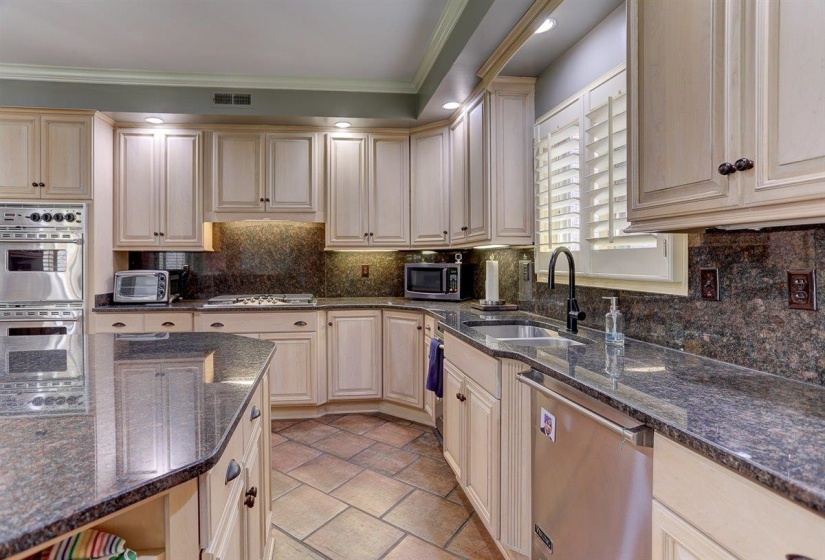 Kitchen featuring appliances with stainless steel finishes, a sink, tasteful backsplash, visible vents, and ornamental molding