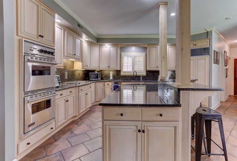 Kitchen featuring crown molding, a kitchen breakfast bar, cream cabinetry, and stainless steel appliances