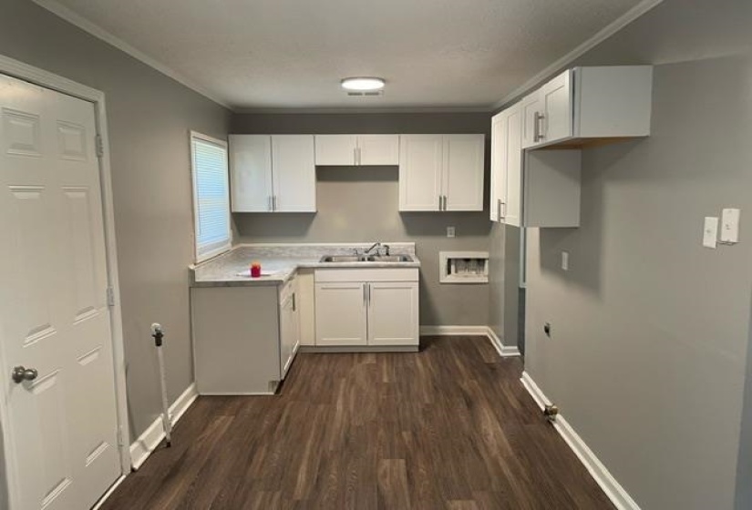 Kitchen featuring dark hardwood / wood-style floors, ornamental molding, sink, and white cabinets