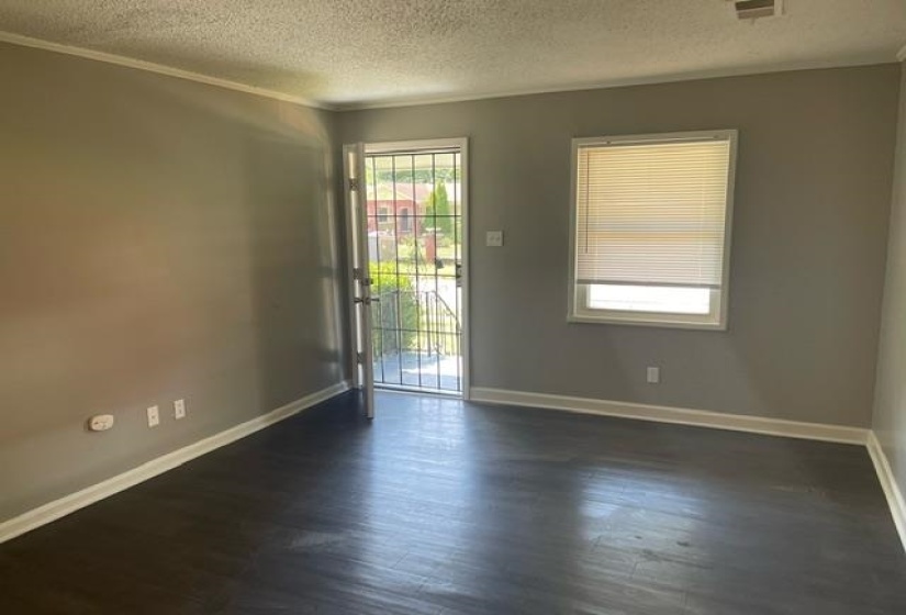 Empty room featuring a textured ceiling and dark hardwood / wood-style floors