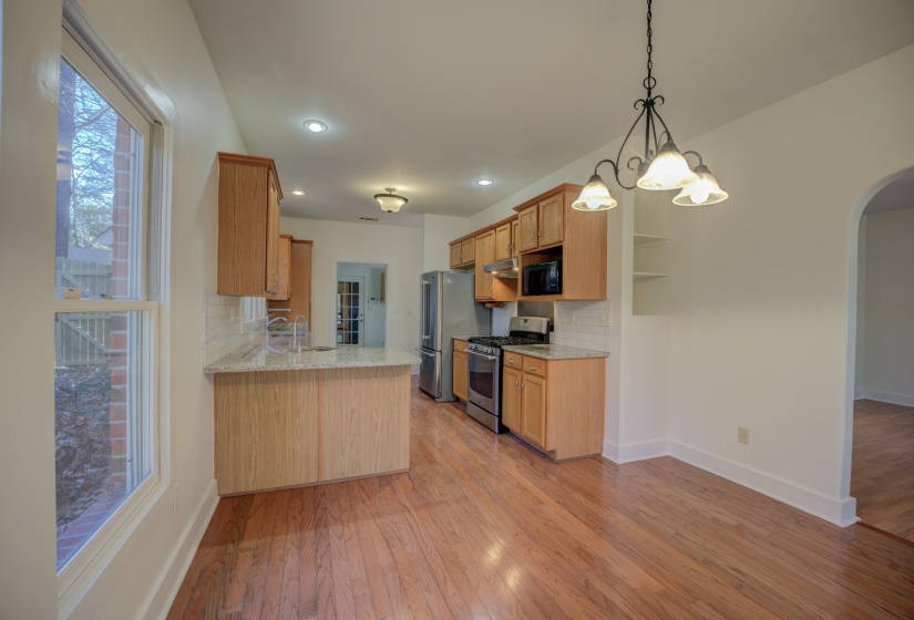 Kitchen with pendant lighting, sink, light hardwood / wood-style flooring, decorative backsplash, and stainless steel appliances