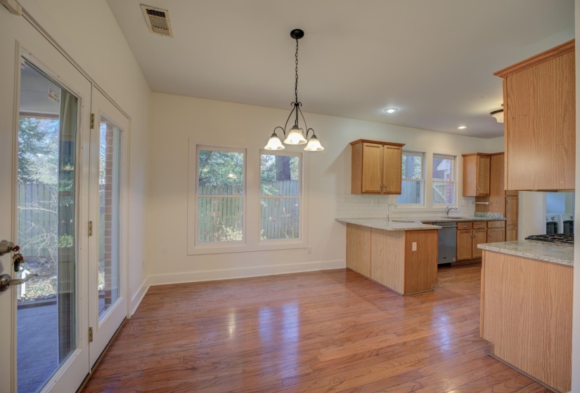 Kitchen with stainless steel dishwasher, kitchen peninsula, a chandelier, decorative light fixtures, and decorative backsplash