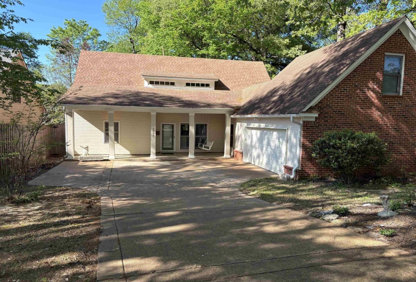 View of front of property featuring an attached garage, covered porch, fence, driveway, and roof with shingles