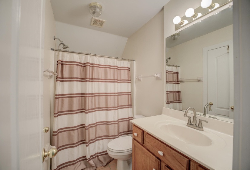 Bathroom with tile patterned flooring, a shower with curtain, vanity, and toilet