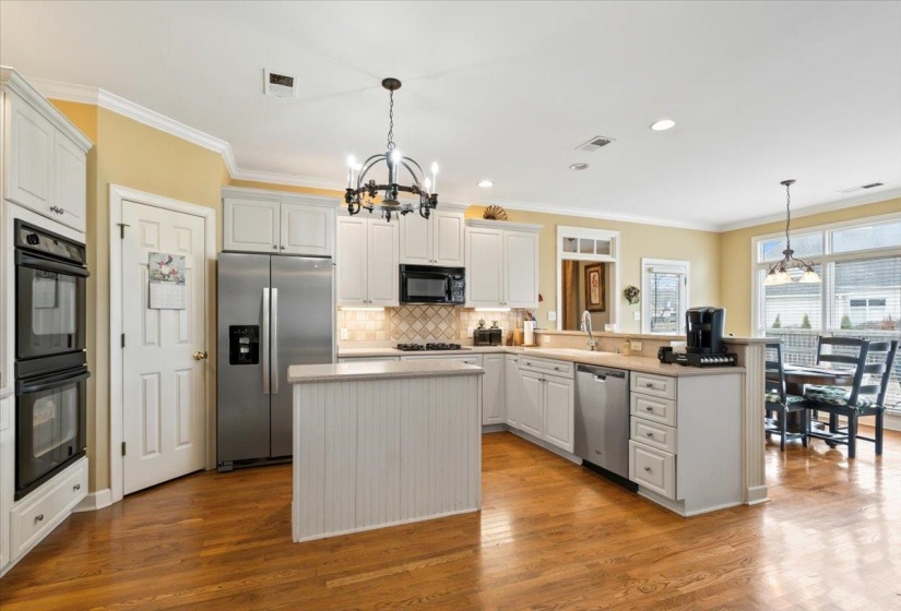Kitchen featuring white cabinetry, a chandelier, hanging light fixtures, a kitchen island, and black appliances