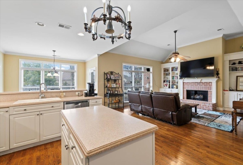 Kitchen with dark hardwood / wood-style floors, a brick fireplace, pendant lighting, a center island, and sink