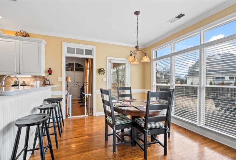 Dining room featuring plenty of natural light, light hardwood / wood-style flooring, crown molding, and a notable chandelier