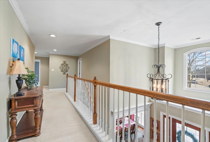 Hallway featuring crown molding, light colored carpet, and an inviting chandelier