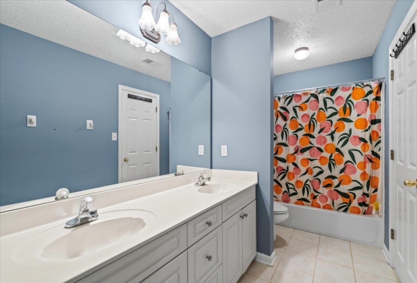 Full bathroom with toilet, shower / bathtub combination with curtain, tile patterned floors, a textured ceiling, and vanity